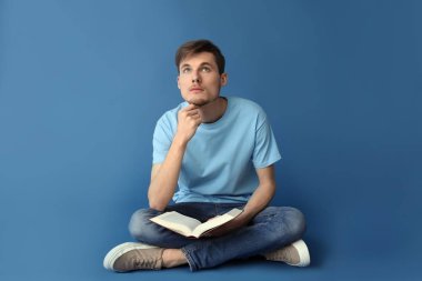 Renklerle ilgili kitabı olan düşünceli bir genç adam.