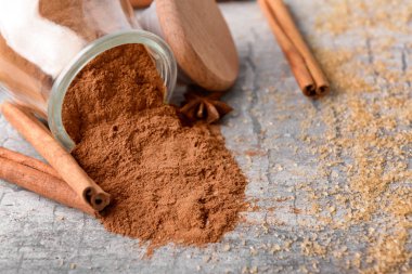 Toz tarçın ve şeker ışık arka plan üzerine devrilmiş kavanoz