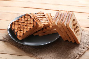 Ahşap masa üzerinde kızarmış ekmek ile plaka