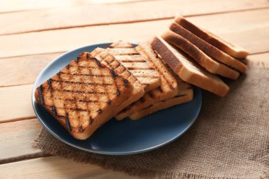 Ahşap masa üzerinde kızarmış ekmek ile plaka