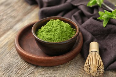 Kase toz matcha yeşil çay ve ahşap masa üzerinde çırpma teli ile