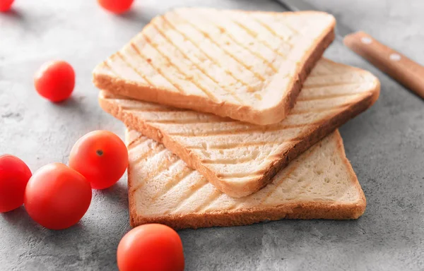 Toasted bread and cherry tomatoes on grey background