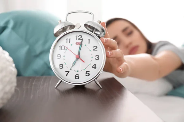 朝のベッドの上の目覚まし時計を持つ若い女性 — ストック写真