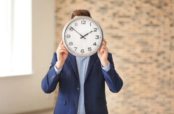 Businessman with clock indoors. Time management concept