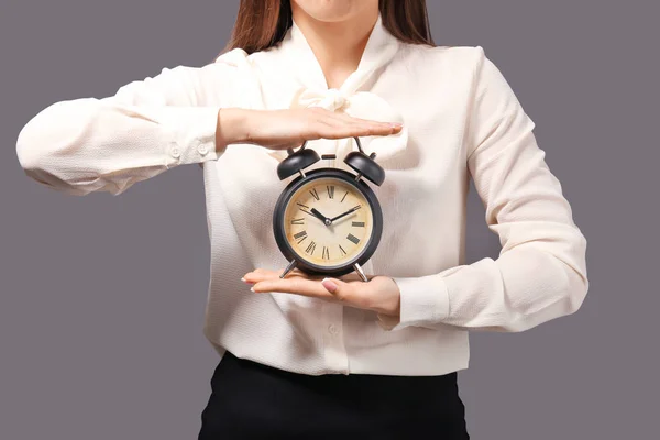 灰色の背景に目覚まし時計と女性 時間管理の概念 — ストック写真