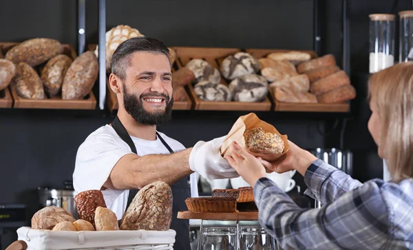 Νεαρός Άνδρας Δίνει Φρέσκο Ψωμί Στη Γυναίκα Στο Αρτοποιείο — Φωτογραφία Αρχείου