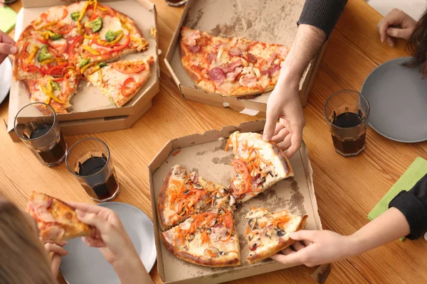 Young people eating pizza at table