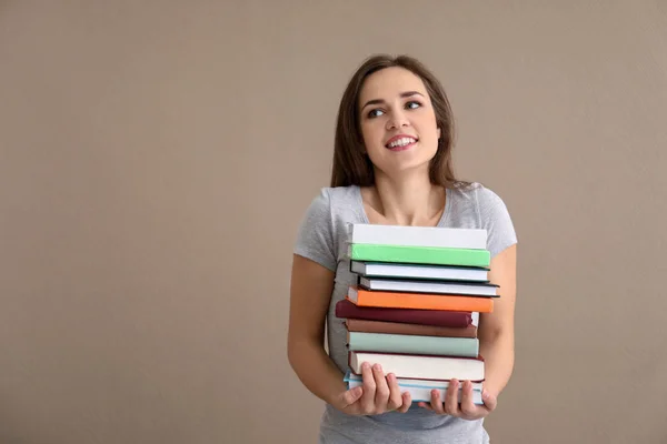 Junge Frau Mit Einem Stapel Bücher Auf Farbigem Hintergrund — Stockfoto