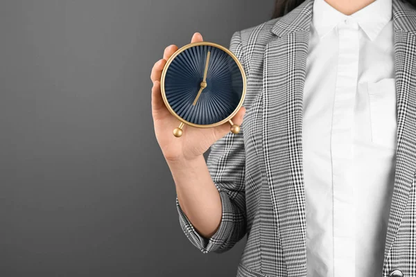 在灰色背景下保持时钟的妇女 时间管理概念 — 图库照片