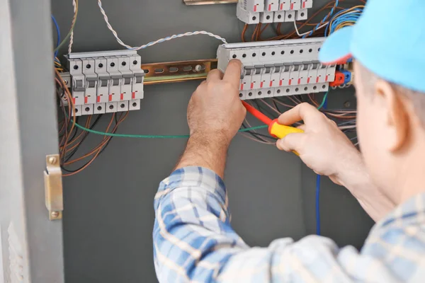 Mature electrician repairing distribution board