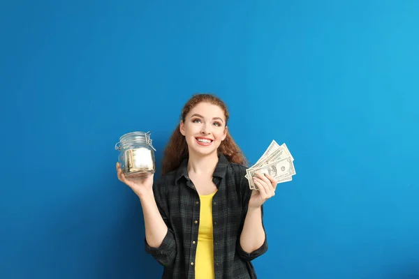 在彩色背景下拿着一张钞票的年轻女子手持玻璃罐子 货币储蓄概念 — 图库照片