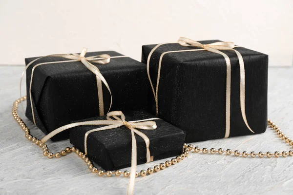 Beautiful gift boxes with beads on light wooden background