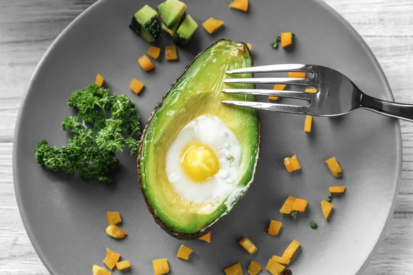 Baked avocado with egg on plate, closeup