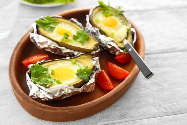 Ahşap masa üzerinde avokado pişmiş yumurta ile plaka