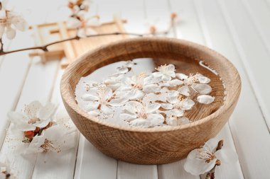 Su ve ahşap zemin üzerine çiçek açan çiçekler ile kase