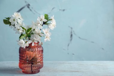 Ahşap masanın üzerinde çiçek açan güzel dalları olan bir vazo.