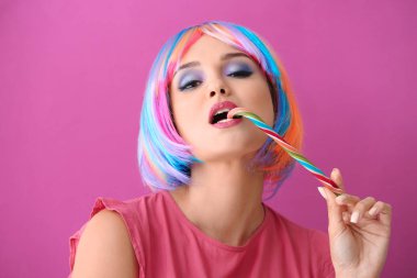 Renk arka plan üzerinde yaratıcı makyaj ve şeker kamışı ile güzel genç kadın