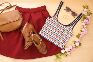 Trendy Bayan giyim ayarla, aksesuarları ve çiçek açması şube, düz ahşap arka plan üzerinde yatıyordu