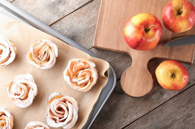 Ahşap masa üzerinde lezzetli gül şekilli elma pasta ile fırın tepsisi