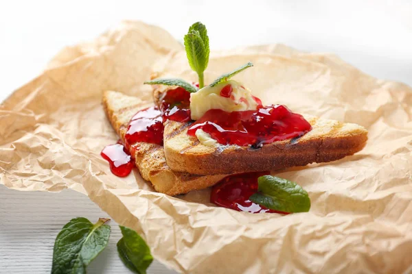 Toasted bread with sweet jam, butter and mint on parchment