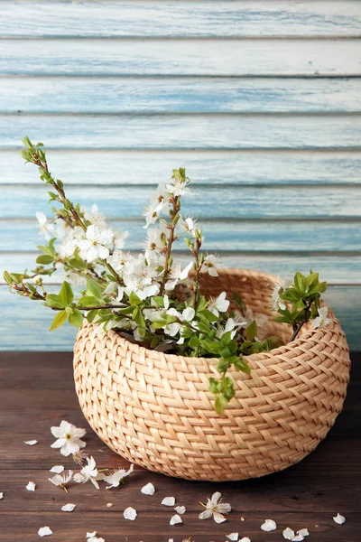 Wicker box with blossoming branches on wooden table