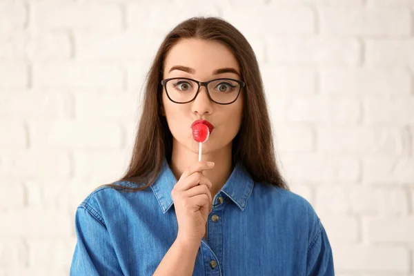 Attractive young woman with lollipop on light background