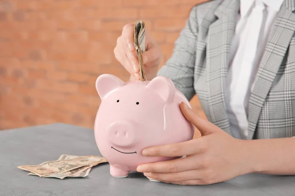 Woman Putting Money Piggy Bank Table — Stock Photo, Image