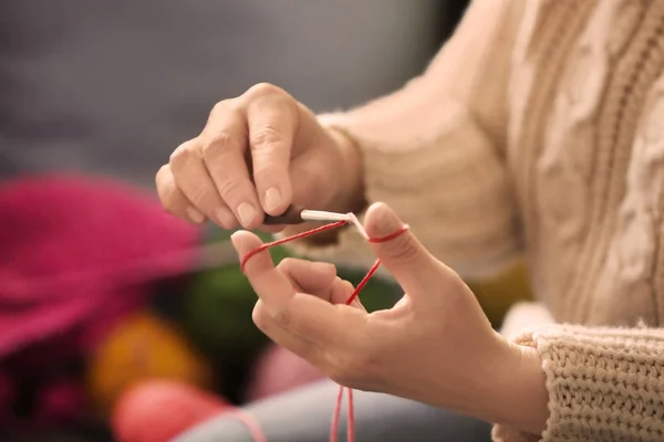 Mature woman knitting warm sweater indoors, closeup