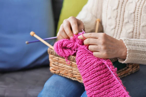 Mature woman knitting warm sweater indoors, closeup