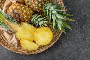 Gri zemin üzerine lezzetli ananas ile hasır plaka