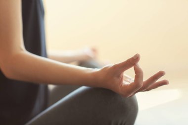 Genç kadın arka planda yoga yapıyor.