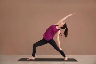 Renkli duvarın yanında yoga yapan genç bir kadın.