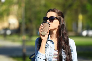 Güzel genç kadın parkta yürürken kahve içme