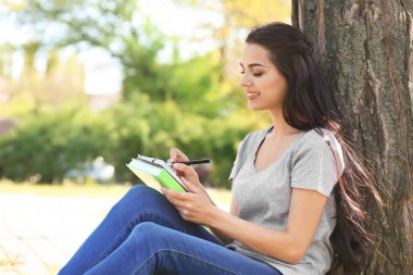 Güzel genç kadın Park'ta dinlenme defter ile