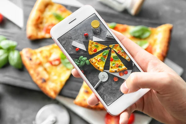 Woman photographing slices of delicious pizza Margherita with mobile phone