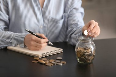 Paralar cam kavanozun içine masanın üzerine koyarak kadın. Tasarruf kavramı