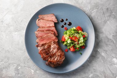 Plakalı gri arka plan üzerinde lezzetli ızgara biftek