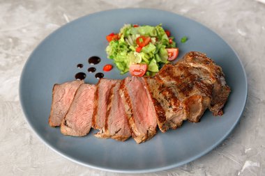 Plakalı gri arka plan üzerinde lezzetli ızgara biftek