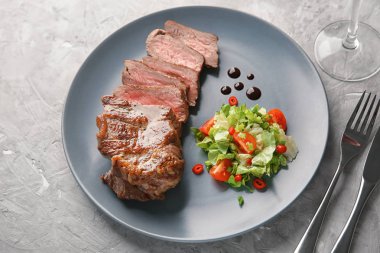 Plakalı gri arka plan üzerinde lezzetli ızgara biftek