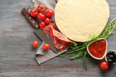 Çiğ hamur ve malzemeler ahşap arka plan üzerinde pizza ile kompozisyon