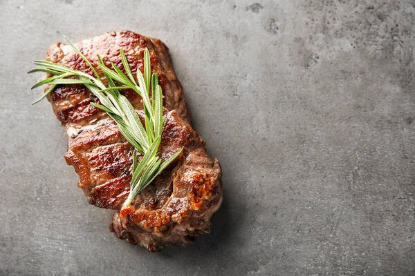 Tasty grilled steak with rosemary on grey background