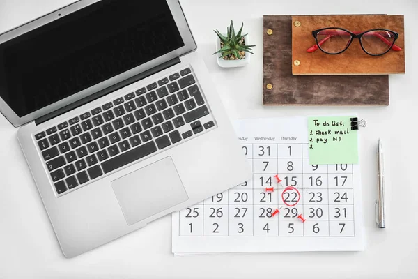 Calendar with notes and laptop on white background