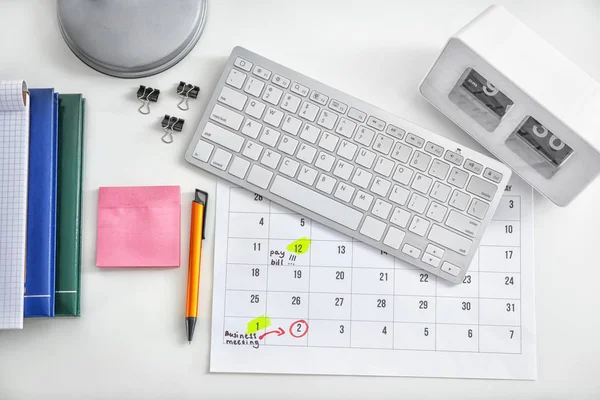 Calendar with notes, computer keyboard and stationery on white background