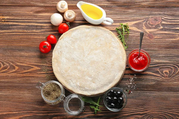 Raw dough with ingredients for pizza on table