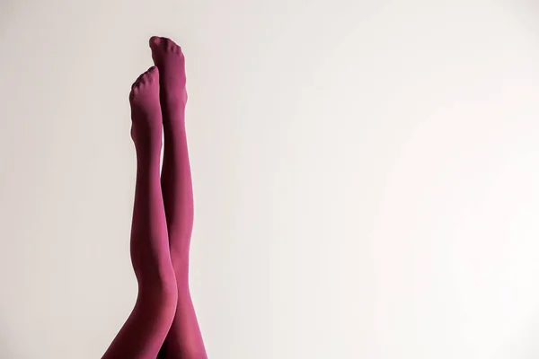 明るい背景に色タイツの美しい若い女性の足 — ストック写真
