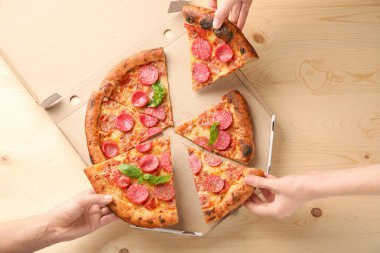 Pizza dilimleri masaya alarak eller
