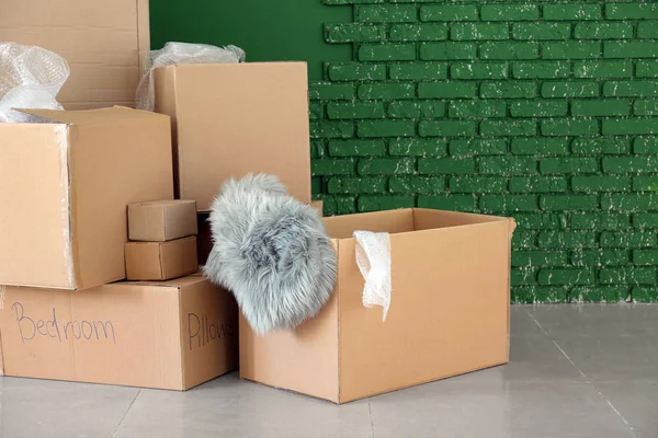 Packed carton boxes near color wall. Moving house concept