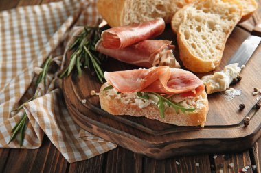 Ahşap tahta üzerinde prosciutto ile lezzetli sandviç