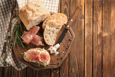 Jambon ve ahşap tahta üzerinde dilimlenmiş ekmek ile lezzetli sandviç