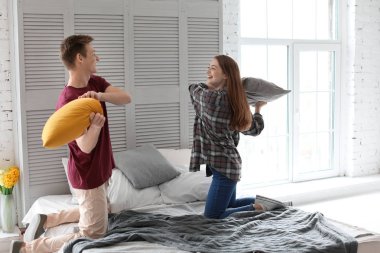 Mutlu genç çift yatakta evde oynarken yumuşak yastık ile